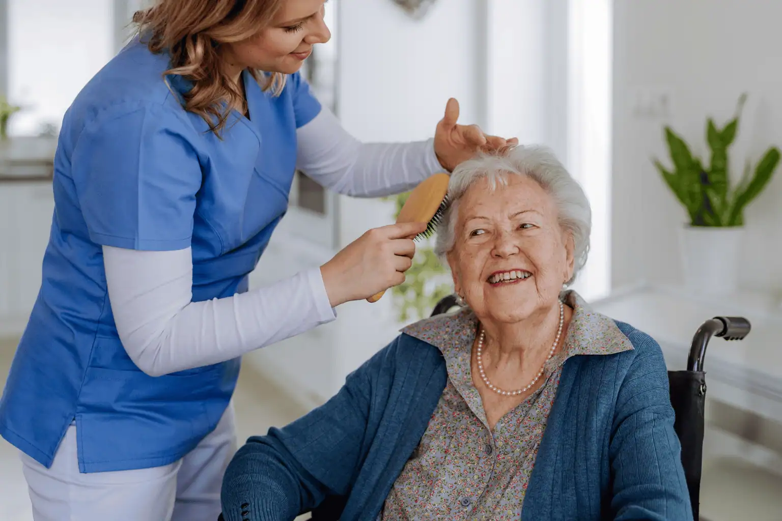 Support worker brushing senior woman's hair