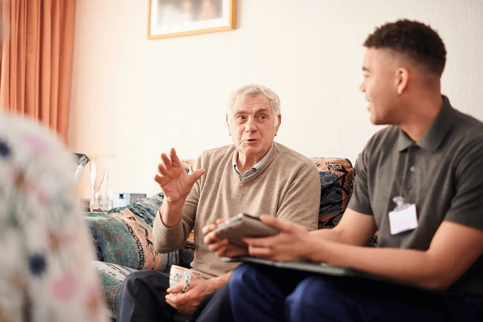 Senior man sitting on couch with support worker